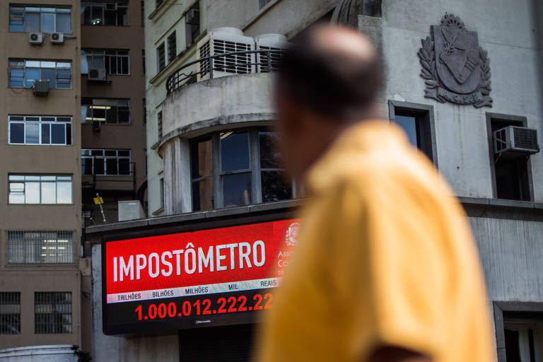 Homem olha para o painel do impostômetro, em São Paulo
