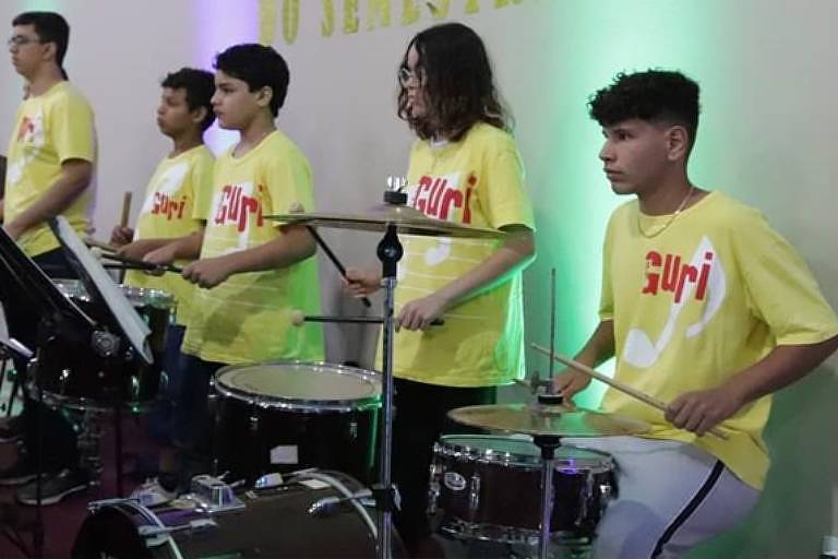 Em foto colorida, alunos do Projeto Guri do Polo Mirante do Paranapanema aparecem tocando instrumentos de percussão