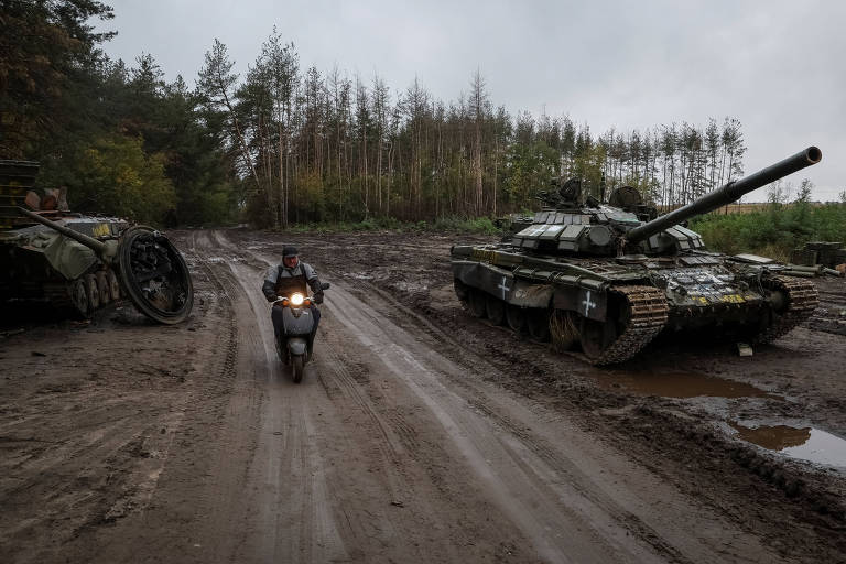 Morador de Izium, retomada pela Ucrânia, passa por tanque e blindado russos destruídos