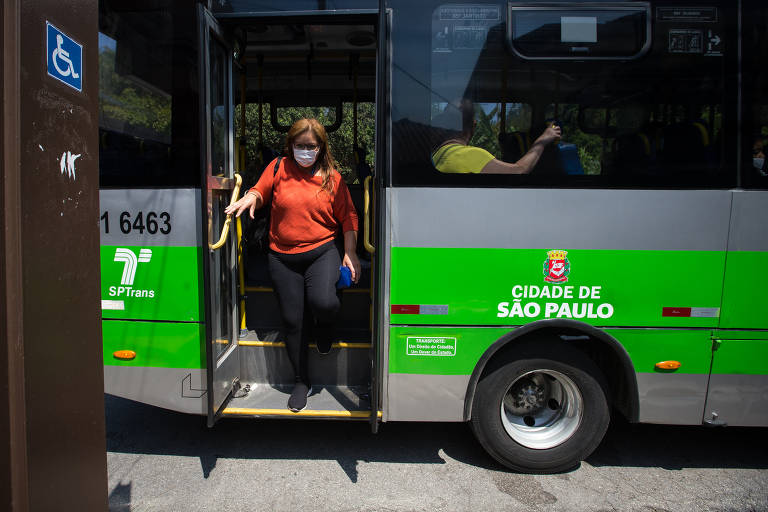 Imagem mostra mulher descendo as escadas da parte de trás de um ônibus da cidade de São Paulo.