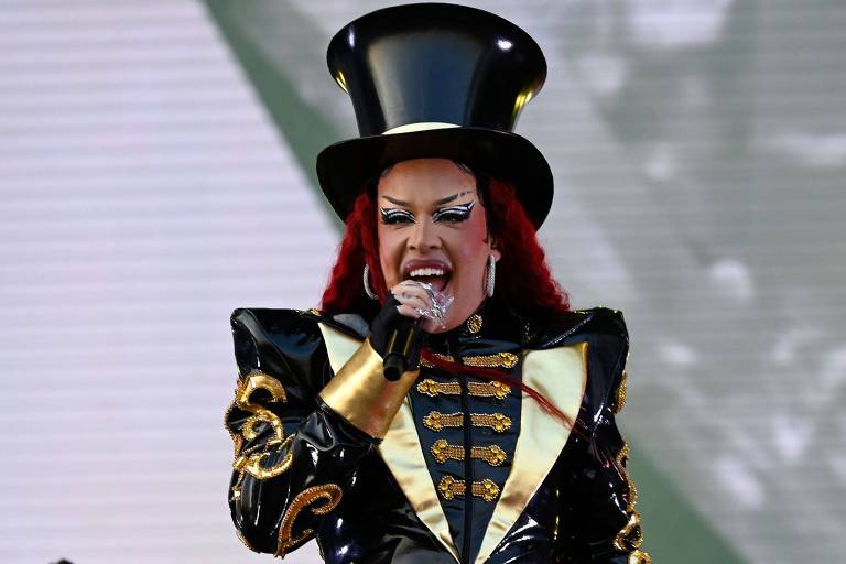 Em foto colorida, cantora sobe ao palco e canta para a plateia em um festival