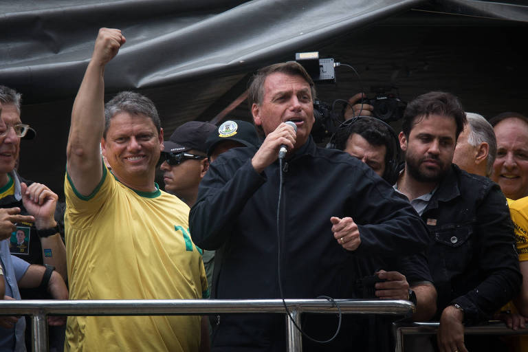 Jair Bolsonaro participa de comício em Sorocaba, ao lado do candidato ao governo de São Paulo Tarcísio de Freitas. Os dois estão em um carro de som. Bolsonaro veste uma jaqueta preta e segura um microfone. Tarcísio, por sua vez, veste camiseta com as cores do Brasil.