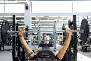 muscular sportsman doing heavy exercise on bench press