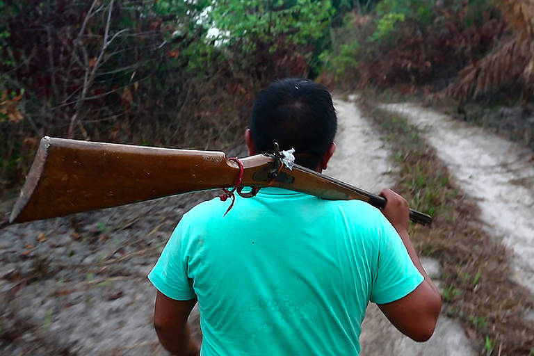 Indígena da etnia Ka'apor é visto de costas segurando uma arma no ombro