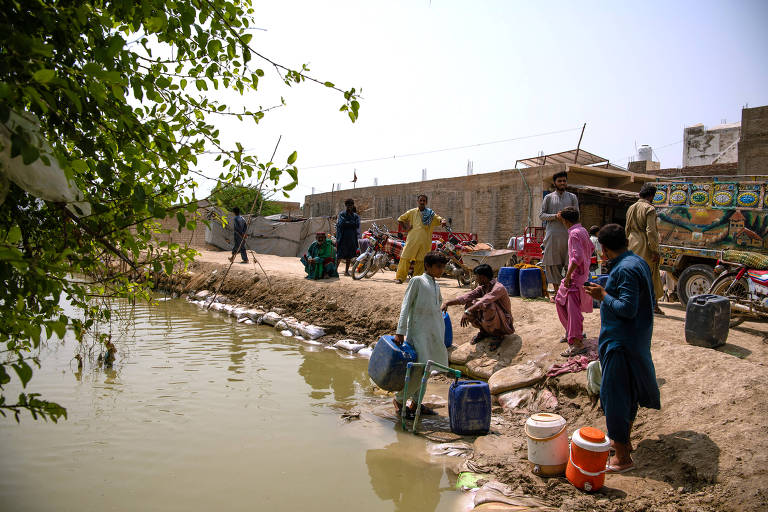 Grupo de pessoas na borda de um lago, carregando baldes para coletar água.