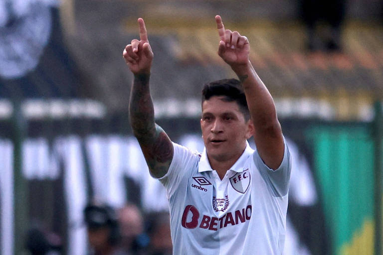 Com os dedos indicadores apontados para o alto, Cano comemora gol pelo Fluminense; a camisa de seu uniforme é branca