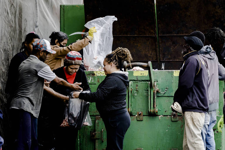 Concentração de pessoas buscam por restos de alimentos em caçamba do Mercado Municipal