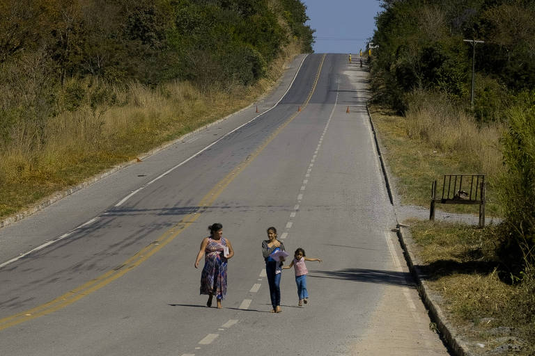 Cena do filme 'Desconectados', da Folha; mãe e filhos caminham no meio da estrada e, bisca de sinal de internet