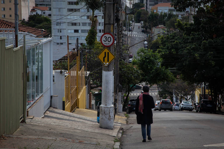 Mulher evita calçada e caminha pela via na rua Caiubi, em Perdizes, zona oeste de São Paulo