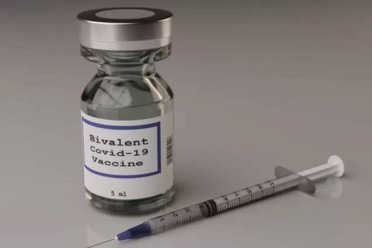Ampola de vacina e seringa. Na ampola, há um adesivo escrito "Vacina bivalente para Covid-19", em inglês.