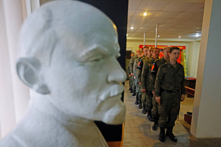 Em uma seção eleitoral adornada com um busto de Lênin, soldados de Lugansk esperam para votar no referendo de anexação na capital da província ocupada
