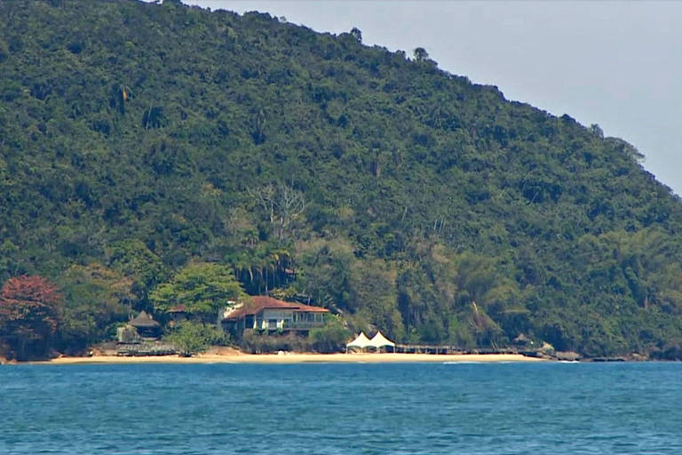 foto distante de ilha em que é possível ver a estrutura de uma mansão 