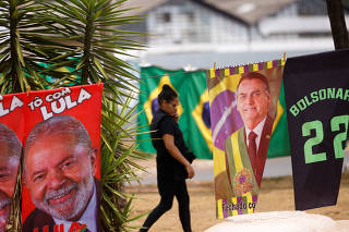 A woman walks past presidential campaign materials depicting Brazil's former President Luiz Inacio Lula da Silva and and President Jair Bolsonaro in Brasilia