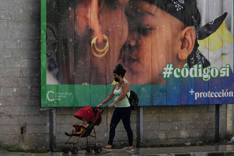 Mulher empurra carrinho de bebê em frente a propaganda a favor do novo Código da Família, em Havana
