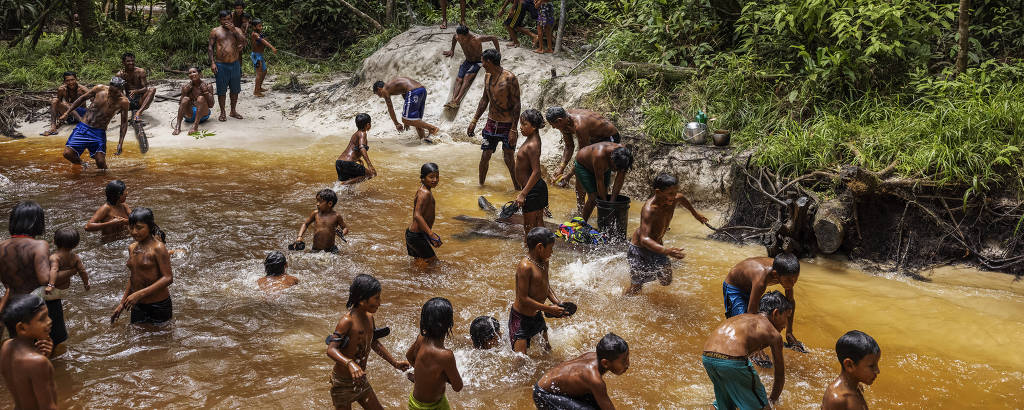 Adultos e crianças brincam em um igarapé próximo à aldeia Mynawa, na terra indígena Waimiri-Atroari, durante encontro para discutir a ameaça ao território e o Marco Temporal
