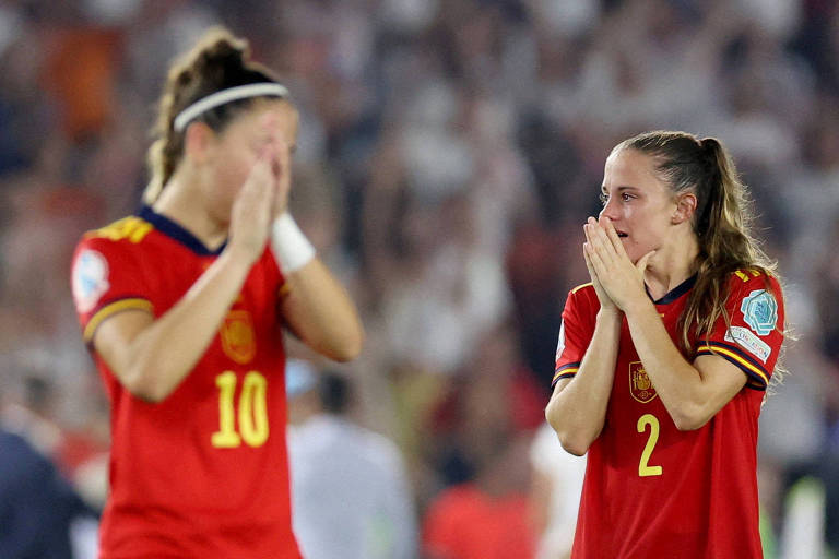 Com as mãos no rosto e usando a camisa vermelha da Espanha, as jogadoras Ona Battle (número 2) e Athenea del Castillo (número 10) lamentam a eliminação da seleção da Eurocopa de 2022, diante da Inglatrerra, em derrota por 2 a 1 em Brighton