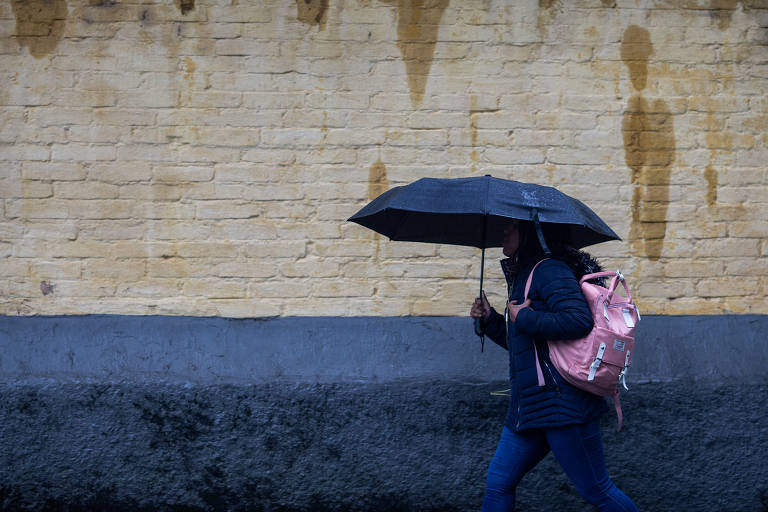 Pedestre se protege de chuva no bairro de Perdizes, em São Paulo