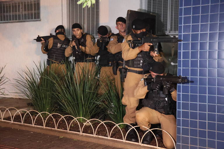 policiais armados com fuzis e coletes e escudo em simulação à noite