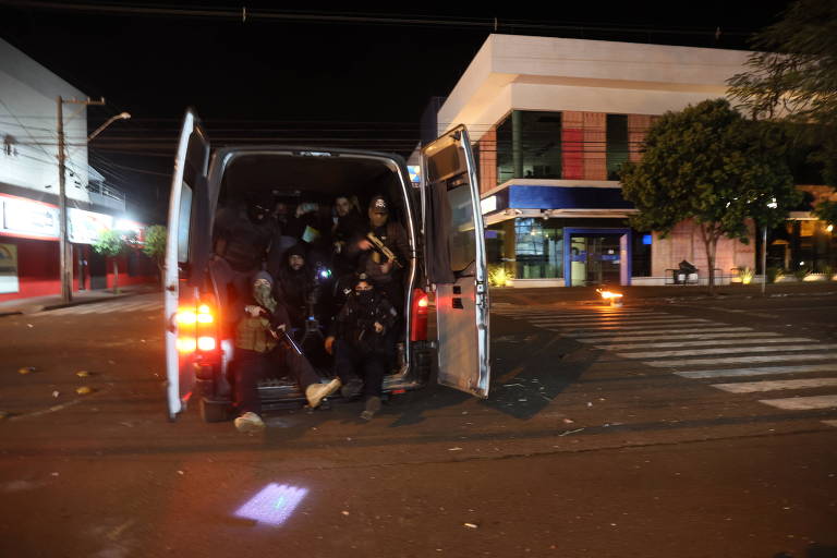 policiais armado com capacete dentro de van em ação à noite