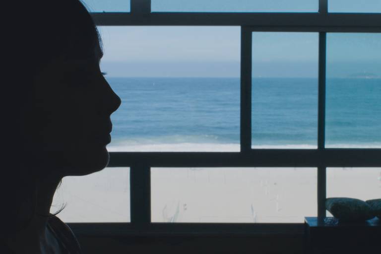 perfil da atriz Simona Spoladore diante de uma janela que dá para ao mar