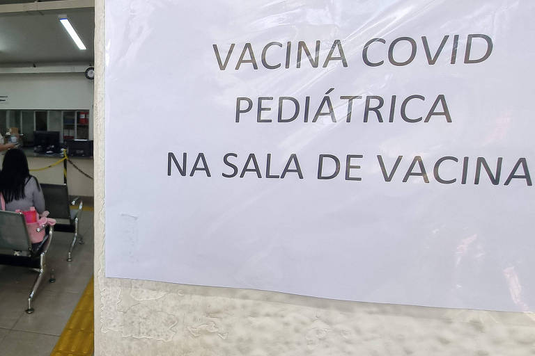 Sala de espera de um posto de saúde com uma placa indicando vacinação pediátrica contra a Covid