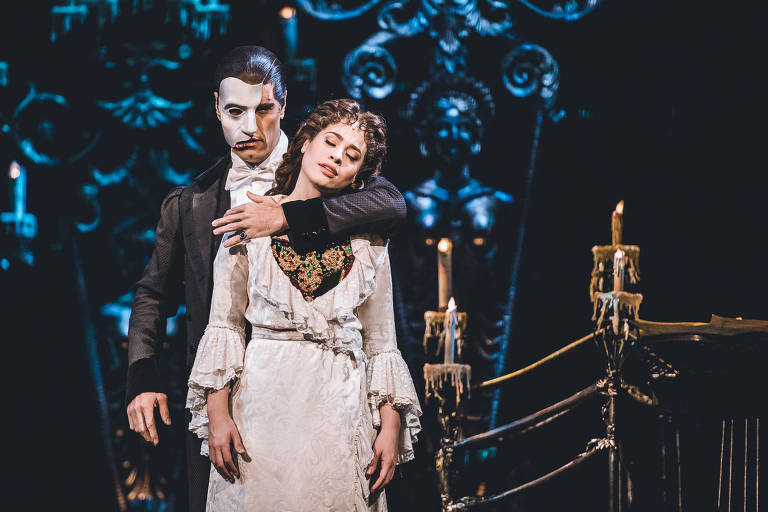 Cena do musical "O Fantasma da Ópera", na qual o fantasma atrás da mocinha, abraçando-a com o braço esquerdo