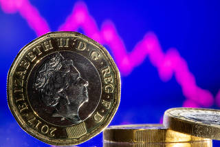 FILE PHOTO: British pound coins are seen in front of displayed stock graph in this illustration