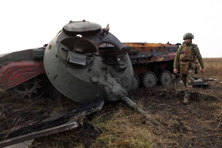 Soldado ucraniano caminha ao lado de tanque russo destruído em Donetsk