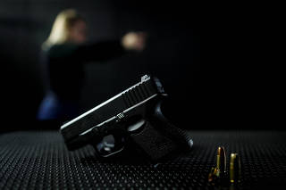 A pistol lies in front of shooter Jacqueline Neves at the shooting range, in Brasilia