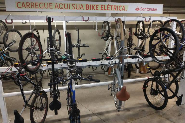Imagem mostra bicicletas carregando em bicicletário.
