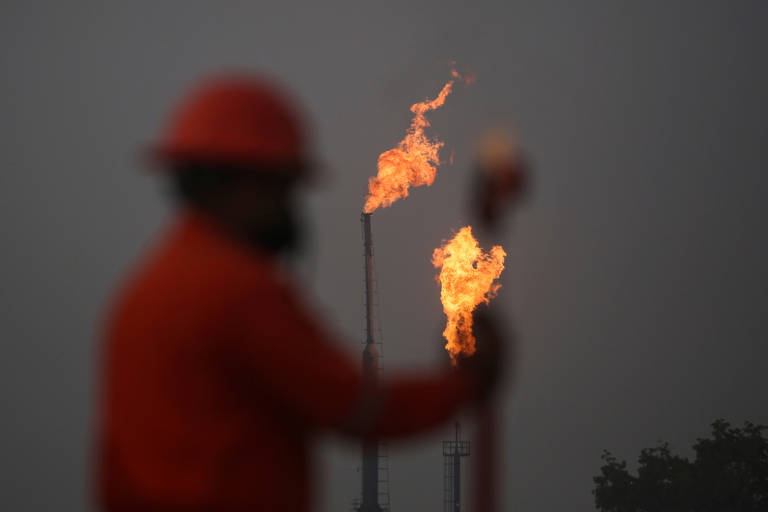 Trabalhador faz medições em frente aos 'flares' queimando metano na companhia Petroleos Mexicanos