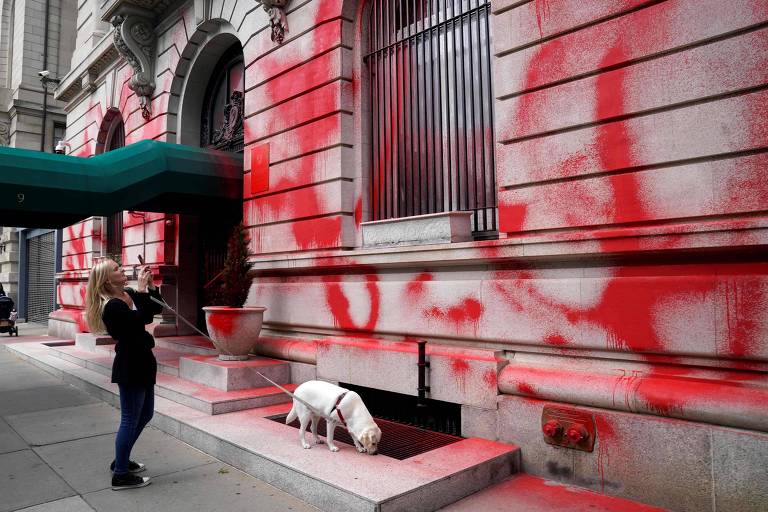 Mulher caminha com cachorro em frente ao consulado da Rússia nos EUA, em Manhattan, alvo de ato de vandalismo
