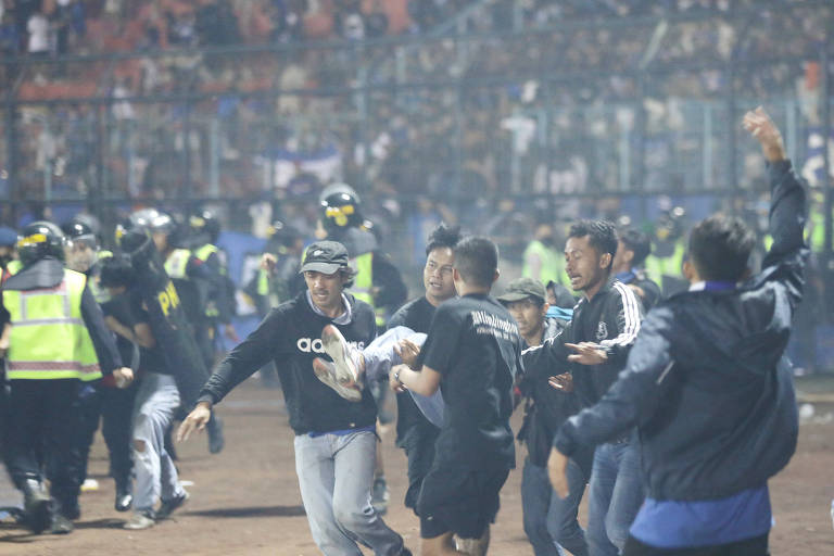Torcedores carregam homem ferido na confusão ocorrida no estádio Kanjuruhan, em Malang, no sábado, quando 125 pessoas morreram