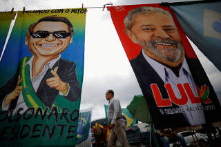 FILE PHOTO: A man walks past presidential campaign materials depicting Brazil's former President Luiz Inacio Lula da Silva and and President Jair Bolsonaro in Brasilia