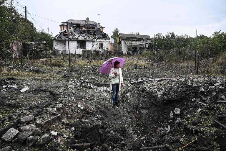 Mulher posa em frente a uma casa destruída, em Kramatorsk, na região de Donetsk