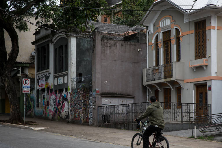 pessoa anda de bicicleta em via do bairro Bexiga, passando na frente de casas em estilo antigo 