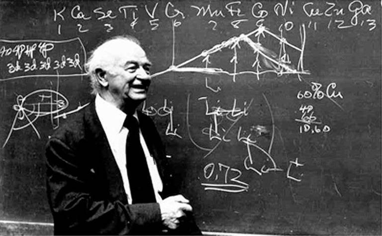 O químico Linus Pauling em frente a uma lousa com fórmulas químicas