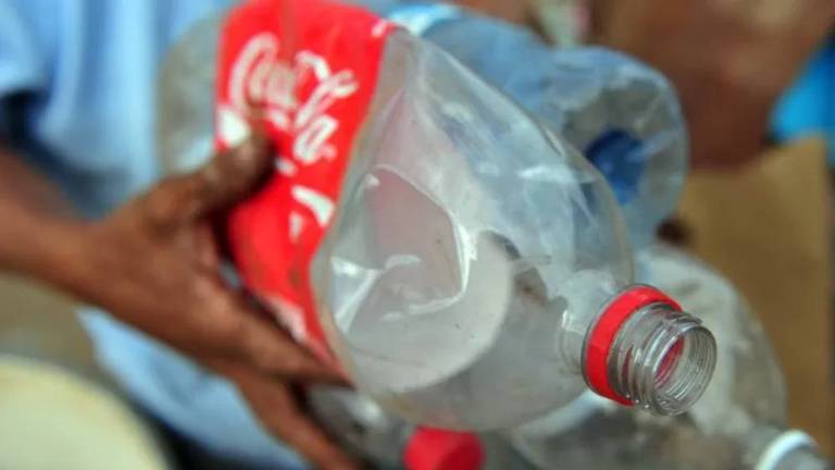 Homem segura uma garrafa plástica da coca-cola