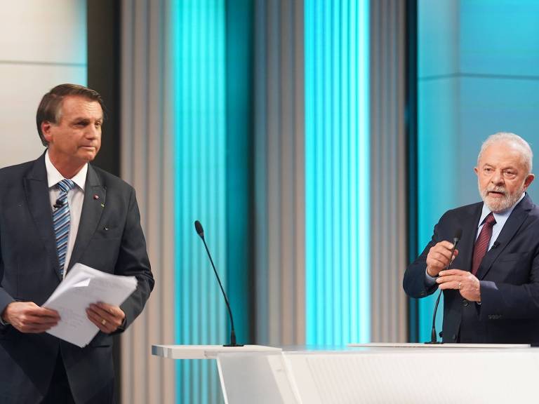 Ambos de terno e gravata e próximos a um púlpito, Bolsonaro e Lula durante debate da TV Globo