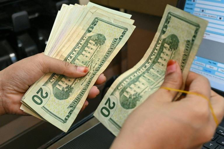 Funcionário de casa de câmbio conta notas de dólar em Singapura