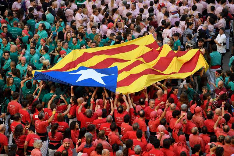 Catalães seguram bandeira do movimento pró-independência da região durante a 28ª edição da competição 'torres humanas', em Tarragona, na Espanha
