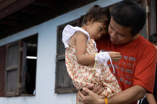 Tawatchai Supolwong holds his daugther Paveenut Supolwong, the only child survivor of the mass shooting in Uthai Sawan