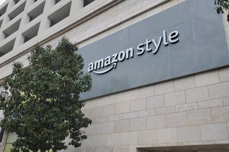 Fotografia colorida de fachada de um prédio com tijolos cinzas e um letreiro com o símbolo de "Amazon Style"