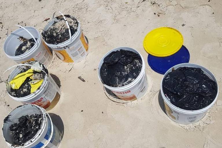 baldes com óleo preto em praia
