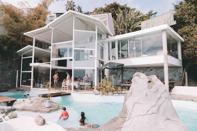 Uma casa de três andares com piscina e paredes de vidro 
