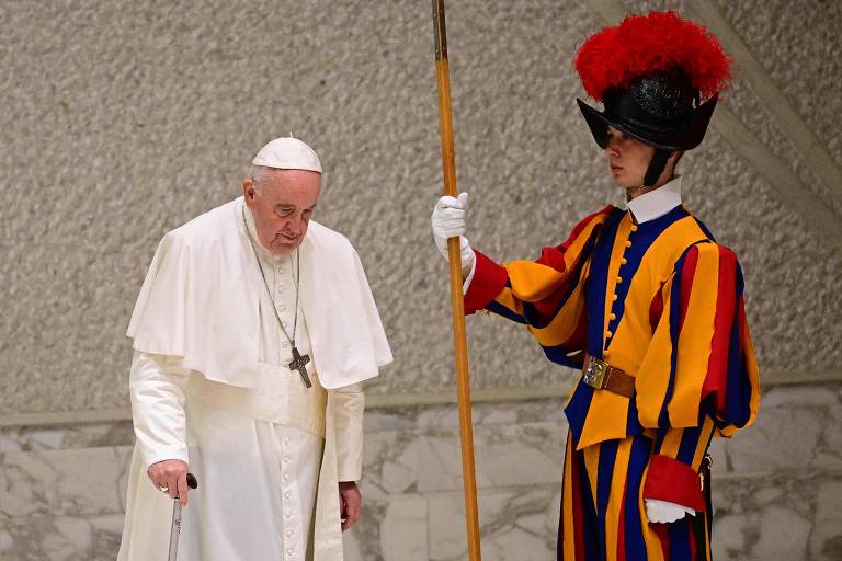 Papa Francisco caminha ao lado de um guarda ao chegar para a audiência-geral no salão Paulo 6º, no Vaticano
