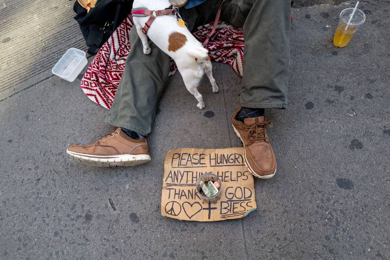 Homem em situação de rua senta com seu cachorro em rua de Manhattan