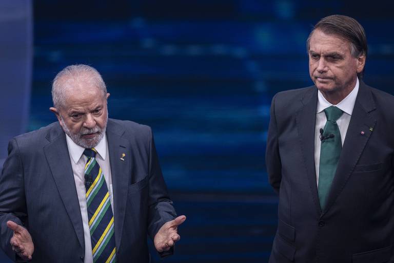 Lula gesticula e Bolsonaro, ao lado, olha para ele