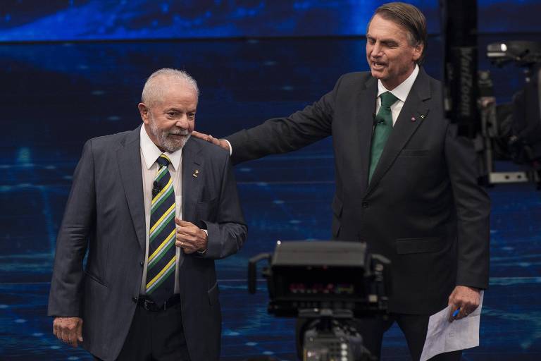 Jair Bolsonaro (à dir) apoia a mão no ombro de Luis Inácio Lula da Silva durante debate dos candidatos a presidente