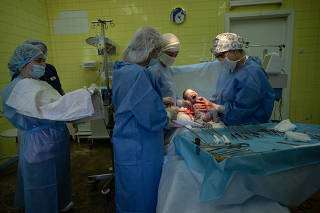 Doctors and nurses deliver a baby born by a Ukrainian surrogate mother  in a hospital in Ukraine?s capital, Kyiv, on Aug. 19, 2022. (Lynsey Addario/The New York Times)